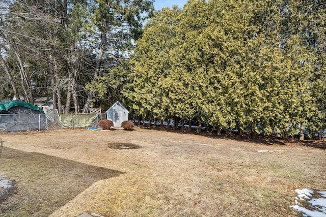 view of yard featuring an outbuilding, a storage shed, and fence