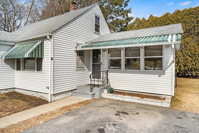 bungalow featuring roof with shingles and a chimney