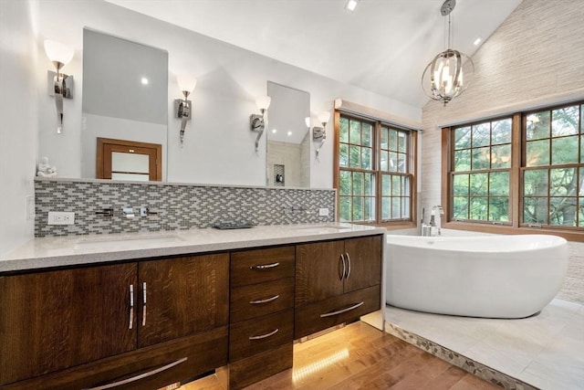 15 Wenlock Cir, Easton, MA 02356 - bathroom with lofted ceiling, double vanity, a freestanding bath, tasteful backsplash, and a chandelier