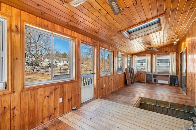 unfurnished sunroom featuring vaulted ceiling with skylight, wooden ceiling, and a ceiling fan