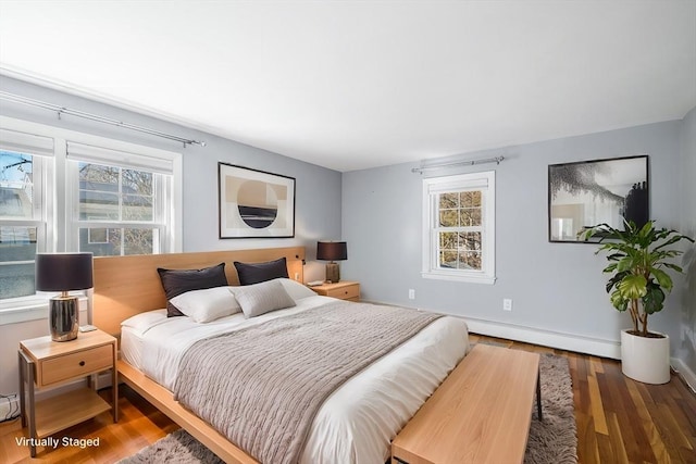 bedroom featuring a baseboard heating unit, wood finished floors, and baseboards