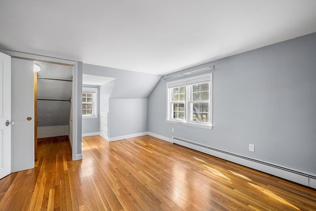 bonus room with a baseboard heating unit, plenty of natural light, lofted ceiling, and wood finished floors