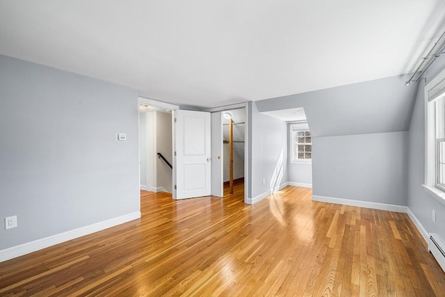 bonus room with light wood-style flooring, baseboards, and a baseboard radiator