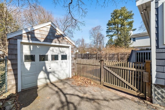 detached garage featuring a gate, fence, and driveway