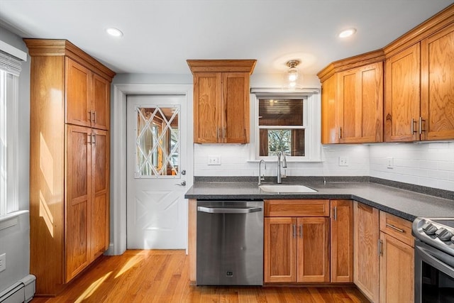 kitchen with a sink, stainless steel appliances, brown cabinets, and a baseboard heating unit