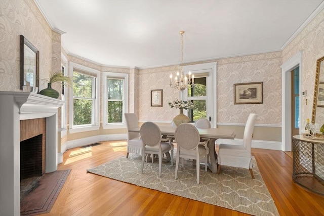 dining room featuring an inviting chandelier, ornamental molding, visible vents, wood finished floors, and wallpapered walls