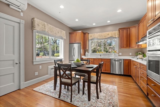 kitchen with a wall mounted AC, light countertops, a sink, light wood-style floors, and stainless steel appliances