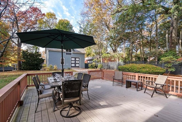 wooden terrace featuring fence, an outbuilding, and outdoor dining space