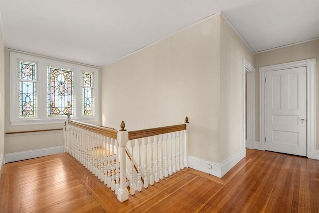 interior space featuring crown molding, baseboards, an upstairs landing, and wood finished floors