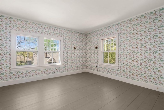 empty room featuring baseboards, crown molding, wood finished floors, and wallpapered walls