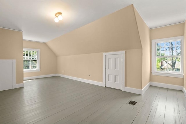 additional living space featuring baseboards, wood finished floors, and visible vents