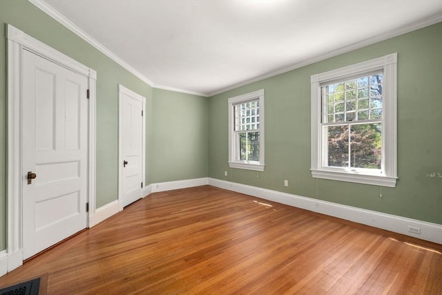 unfurnished room with baseboards, ornamental molding, and light wood finished floors