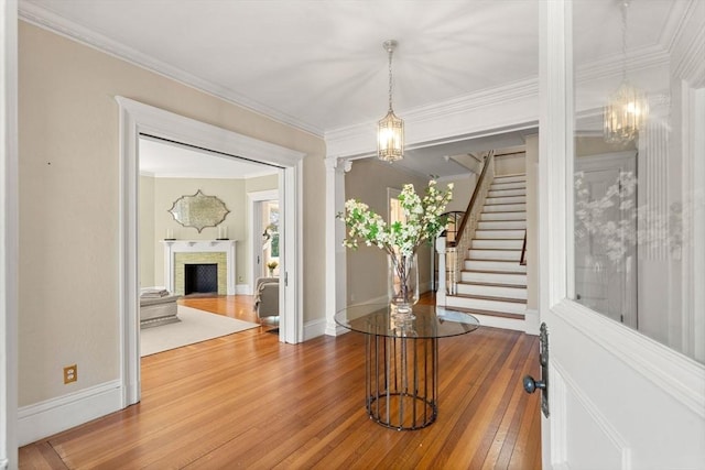 unfurnished dining area featuring crown molding, a fireplace, hardwood / wood-style flooring, stairway, and a notable chandelier