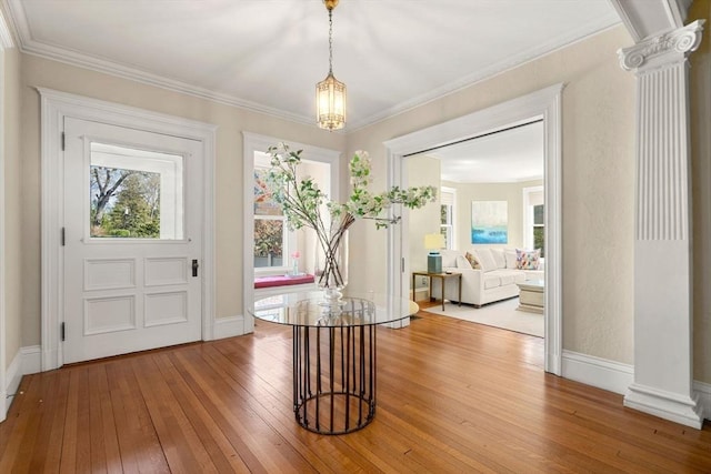 foyer entrance featuring crown molding, baseboards, decorative columns, and hardwood / wood-style floors