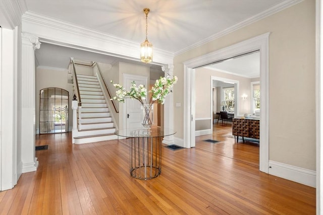 foyer entrance with stairs, baseboards, ornamental molding, and light wood-style floors