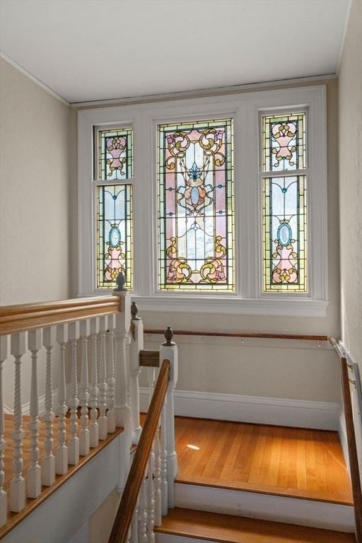 stairway with crown molding, baseboards, and wood finished floors