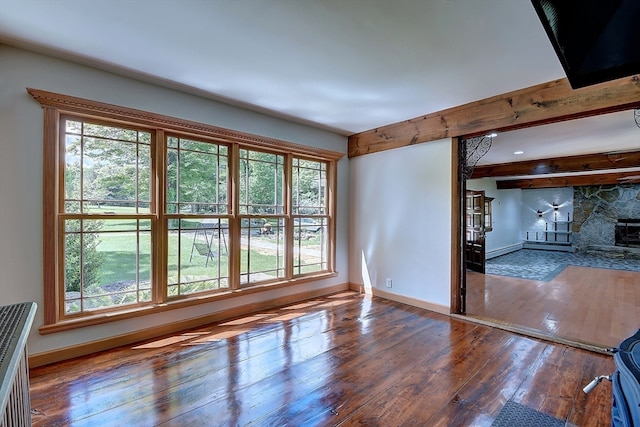 unfurnished living room with wood-type flooring and beam ceiling