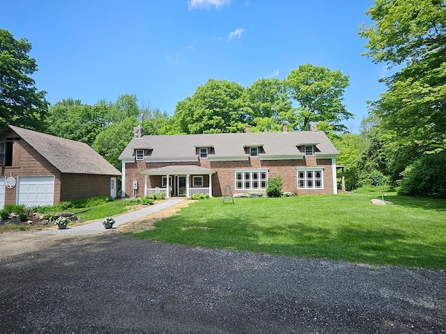 view of front of property featuring an outbuilding, a garage, a front lawn, and covered porch