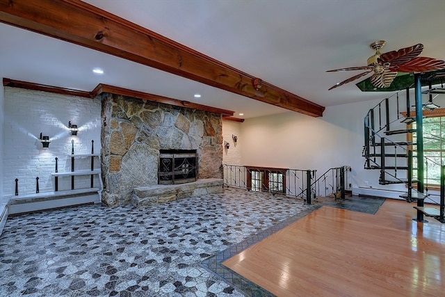 unfurnished living room featuring a fireplace, beam ceiling, hardwood / wood-style flooring, and ceiling fan