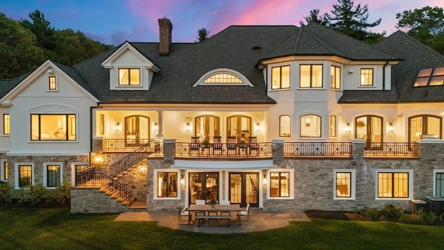 6 Wayside Cir, Framingham, MA 01701 - back of property at dusk with a chimney, stairway, stucco siding, and stone siding