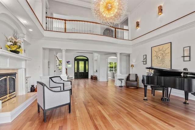 6 Wayside Cir, Framingham, MA 01701 - living area with decorative columns, a towering ceiling, light wood-style flooring, a chandelier, and a premium fireplace
