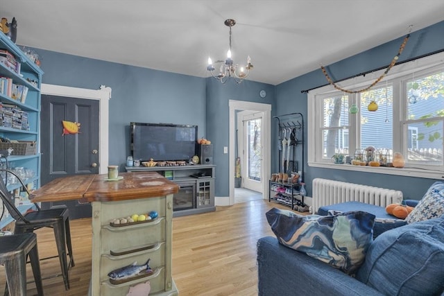 living area with baseboards, an inviting chandelier, radiator, and wood finished floors