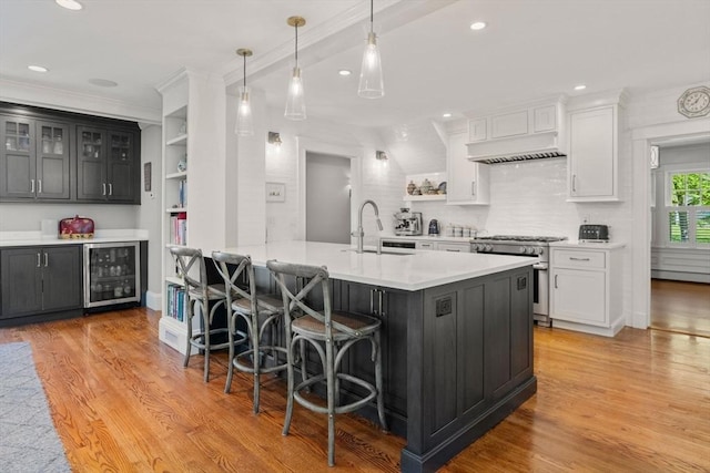 kitchen featuring high end range, a kitchen breakfast bar, a sink, and light wood-type flooring