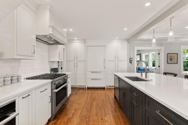 kitchen with decorative backsplash, appliances with stainless steel finishes, a sink, light countertops, and white cabinetry