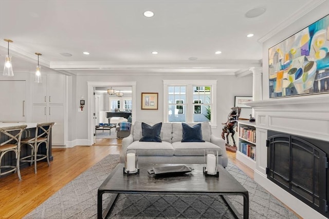 living area featuring recessed lighting, ornamental molding, light wood-style flooring, and a fireplace