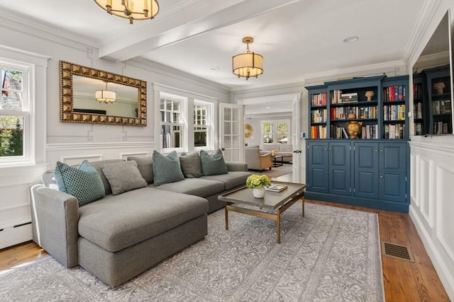 living area featuring visible vents, crown molding, and wood finished floors