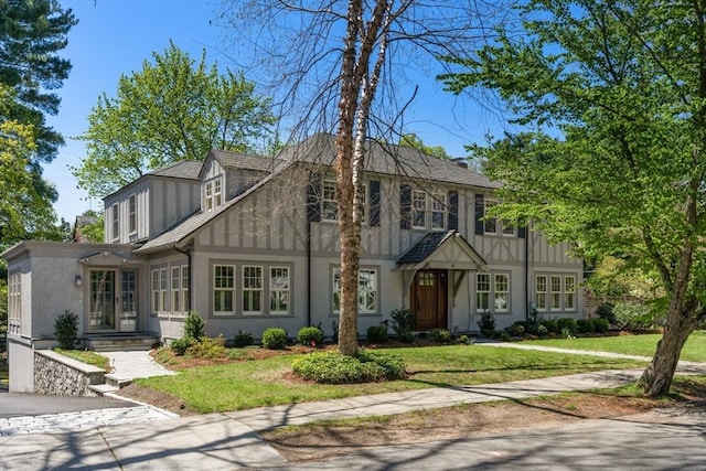 tudor-style house featuring stucco siding and a front lawn