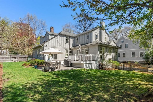 rear view of house featuring a lawn, a chimney, a fenced backyard, and a patio area