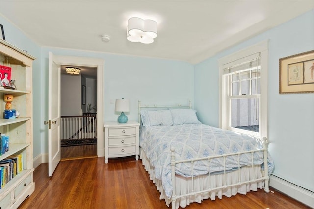 bedroom with baseboards, a baseboard radiator, and wood finished floors