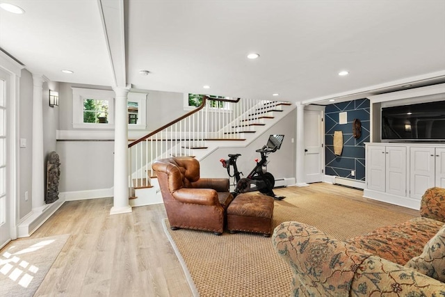 living area featuring stairway, baseboards, decorative columns, and light wood-style flooring