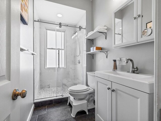 full bathroom with baseboards, a marble finish shower, toilet, and vanity