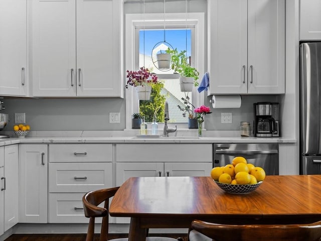 kitchen with a sink, white cabinets, appliances with stainless steel finishes, and a wealth of natural light