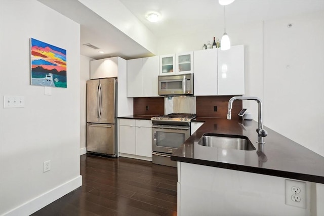 kitchen featuring backsplash, sink, dark hardwood / wood-style flooring, white cabinetry, and stainless steel appliances