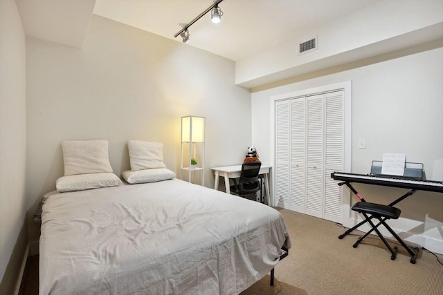 carpeted bedroom featuring a closet and track lighting