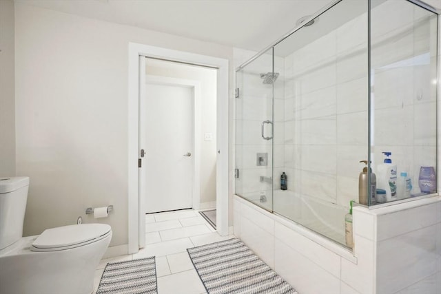 bathroom with toilet, tile patterned floors, and shower / bath combination with glass door