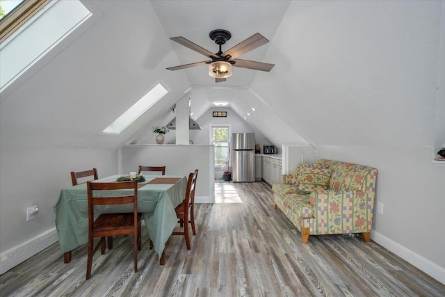 dining area with a skylight, vaulted ceiling, light wood-type flooring, ceiling fan, and baseboards