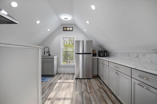 bonus room with lofted ceiling, wood finished floors, and a sink