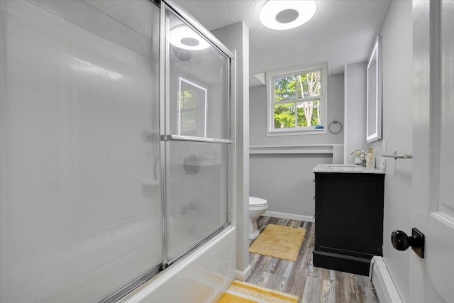 full bathroom with wood finished floors, toilet, vanity, shower / bath combination with glass door, and a baseboard radiator