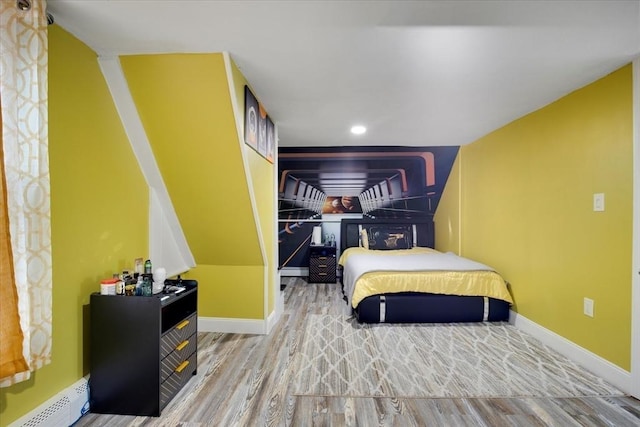 bedroom with a baseboard radiator, wood finished floors, and baseboards