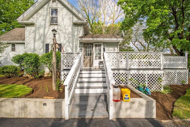 view of front of property featuring a wooden deck and a shingled roof