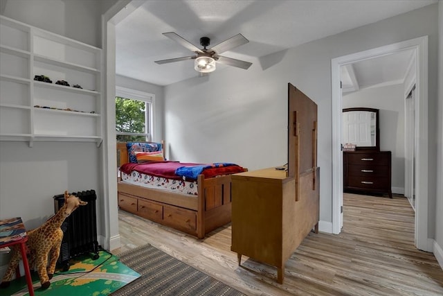 bedroom featuring light wood-style floors, baseboards, a ceiling fan, and lofted ceiling