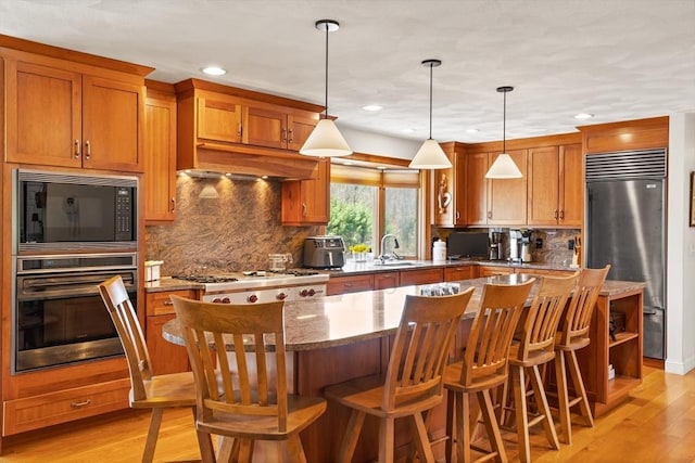 10 Deer Run Dr, Westford, MA 01886 - kitchen with brown cabinetry, a center island, light wood-type flooring, a sink, and built in appliances