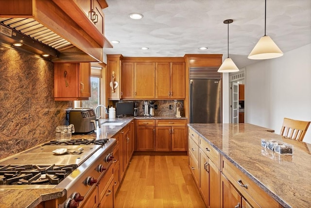10 Deer Run Dr, Westford, MA 01886 - kitchen with brown cabinetry, premium range hood, light wood-type flooring, a sink, and stainless steel appliances