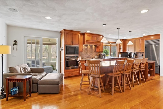 10 Deer Run Dr, Westford, MA 01886 - kitchen featuring decorative backsplash, light wood finished floors, built in appliances, and a breakfast bar