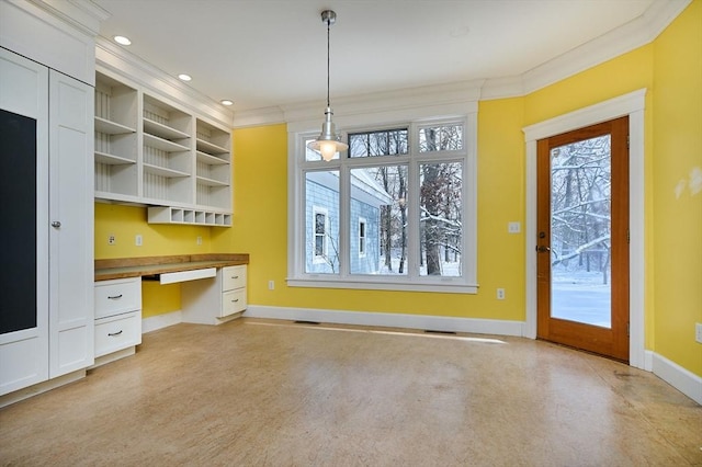 kitchen with ornamental molding, built in desk, white cabinets, and decorative light fixtures