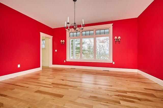 unfurnished dining area with an inviting chandelier and wood-type flooring